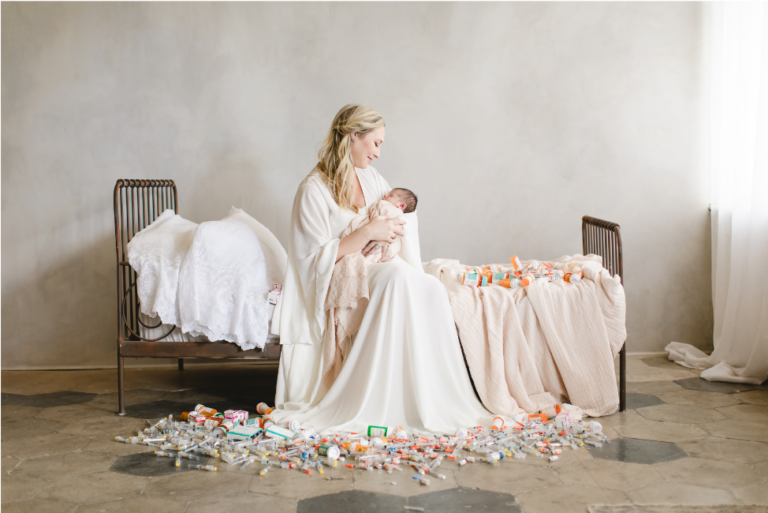 professional portraint of new mom draped in pretty robes while holding a newborn.