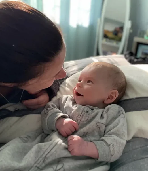 Kerri Morgan leaning over her baby who is smiling up at her.