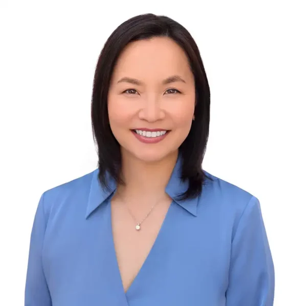Sunny Jun, a young woman with black hair, smiling wearing a blue collared shirt.