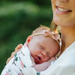 Newborn sleeping peacefully against her mother's chest.